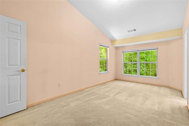 empty room with vaulted ceiling and light colored carpet