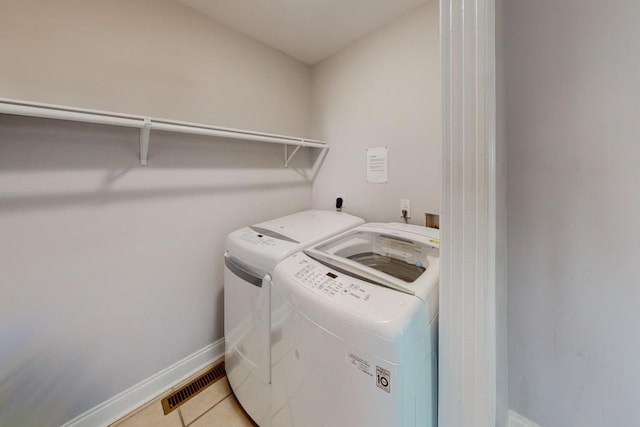 clothes washing area with visible vents, baseboards, light tile patterned floors, laundry area, and washer and dryer