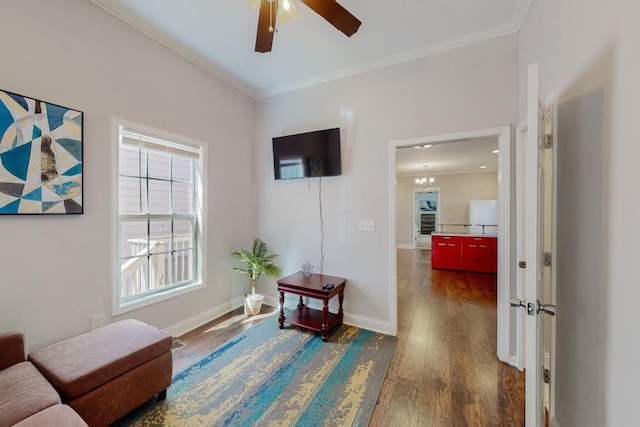 sitting room featuring ceiling fan, baseboards, dark wood finished floors, and ornamental molding