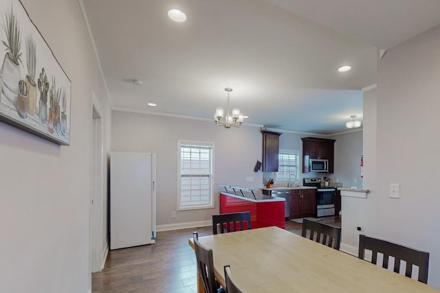 dining room with baseboards, dark wood finished floors, recessed lighting, ornamental molding, and a notable chandelier