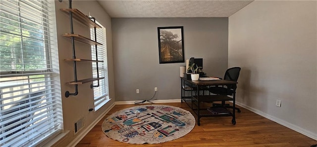 home office with hardwood / wood-style floors and a textured ceiling