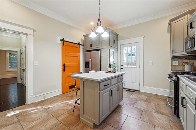 kitchen featuring a barn door, stainless steel appliances, crown molding, and gray cabinetry