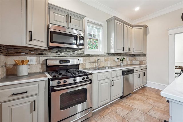 kitchen featuring crown molding, gray cabinets, light countertops, appliances with stainless steel finishes, and a sink