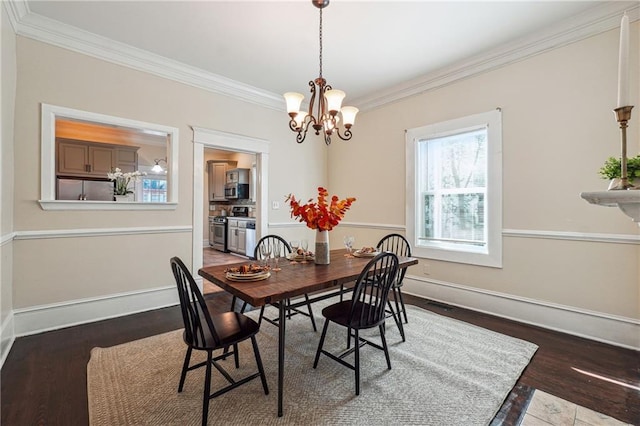 dining area featuring baseboards, a notable chandelier, ornamental molding, and wood finished floors