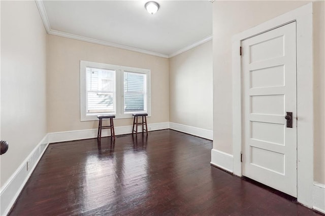 spare room featuring ornamental molding, baseboards, and wood finished floors