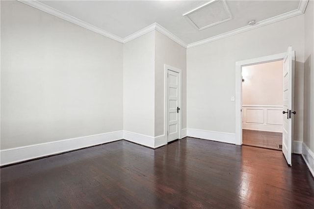 spare room featuring attic access, dark wood finished floors, baseboards, and ornamental molding