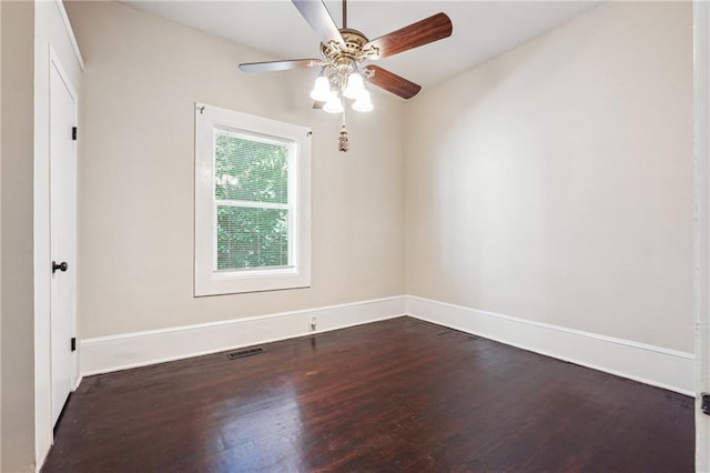 spare room featuring dark wood-type flooring, visible vents, baseboards, and a ceiling fan