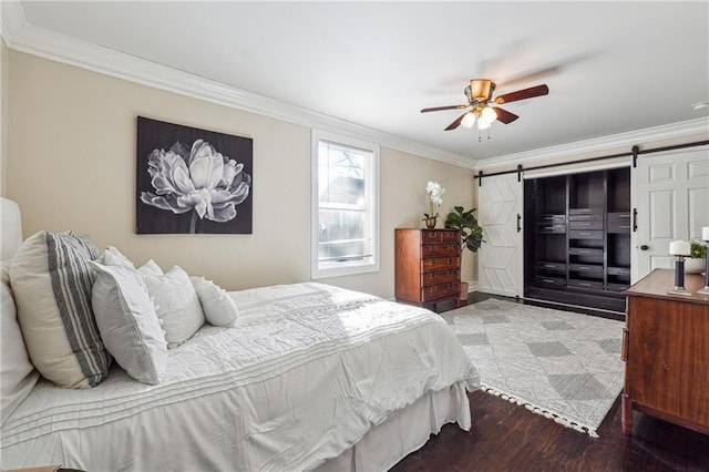 bedroom with dark wood-type flooring, crown molding, ceiling fan, and a barn door