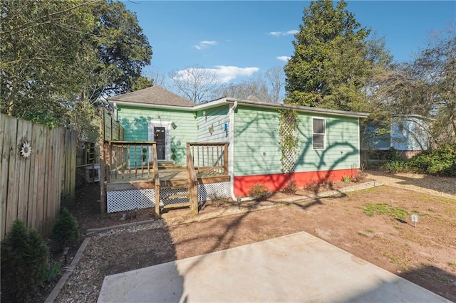 rear view of house featuring fence and a wooden deck