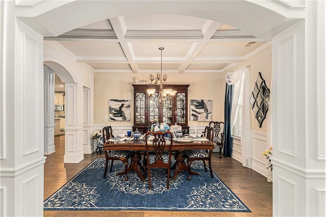 dining area featuring dark wood-type flooring, beamed ceiling, coffered ceiling, and ornate columns