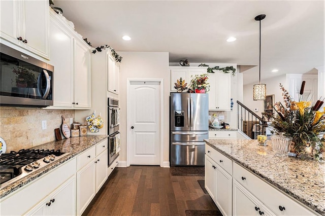 kitchen featuring dark wood-type flooring, white cabinets, decorative backsplash, appliances with stainless steel finishes, and decorative light fixtures