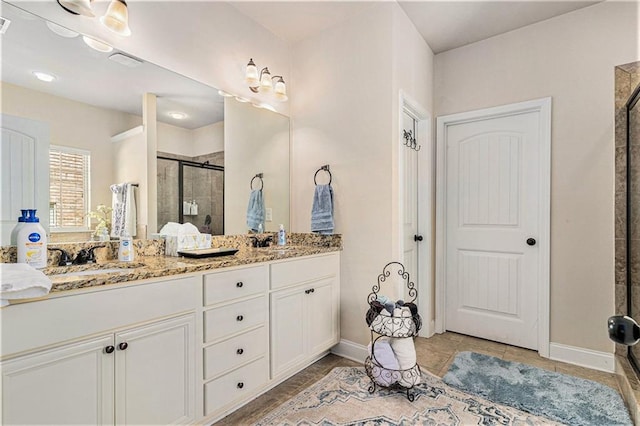 bathroom featuring a shower with shower door and vanity