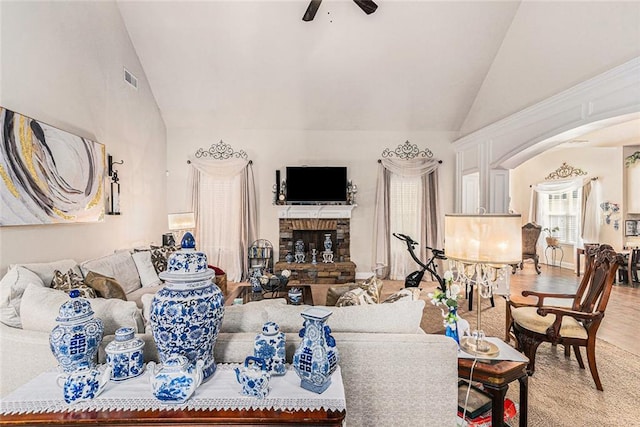 living room with a brick fireplace, hardwood / wood-style flooring, ceiling fan, and vaulted ceiling