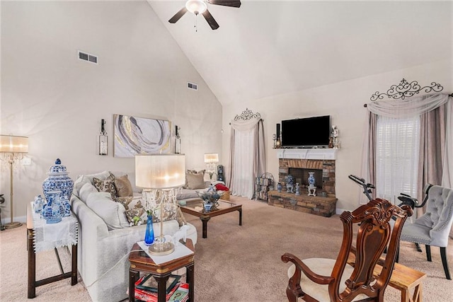 carpeted living room with ceiling fan, a stone fireplace, and high vaulted ceiling