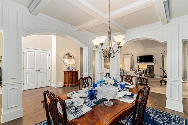 dining area with dark hardwood / wood-style flooring, beam ceiling, a chandelier, and decorative columns