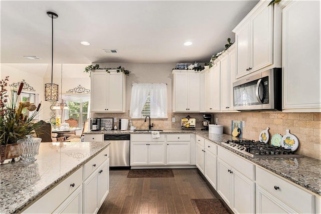 kitchen with light stone counters, white cabinetry, appliances with stainless steel finishes, dark hardwood / wood-style floors, and hanging light fixtures