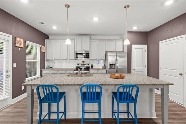 560 Vandenburg Dr, Villa Rica, GA 30180 - kitchen with stainless steel appliances, wood finished floors, a kitchen island with sink, backsplash, and a kitchen bar