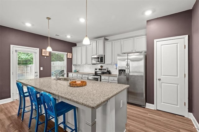 560 Vandenburg Dr, Villa Rica, GA 30180 - kitchen with stainless steel appliances, light wood-style flooring, a kitchen island with sink, a breakfast bar area, and recessed lighting
