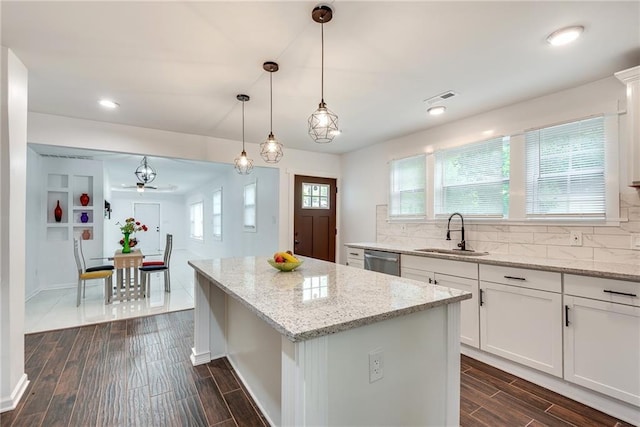 kitchen featuring sink, dishwasher, white cabinetry, hanging light fixtures, and a kitchen island