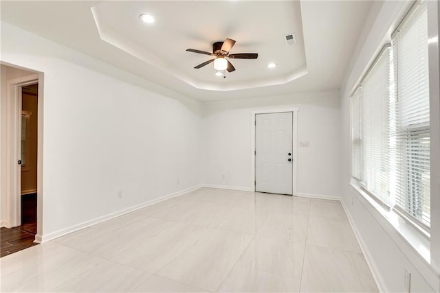 empty room with a tray ceiling and ceiling fan