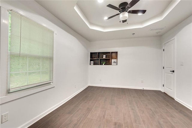 spare room featuring a raised ceiling, wood-type flooring, and ceiling fan