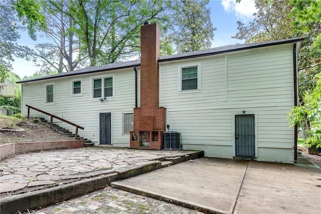 back of property with central AC unit and a patio