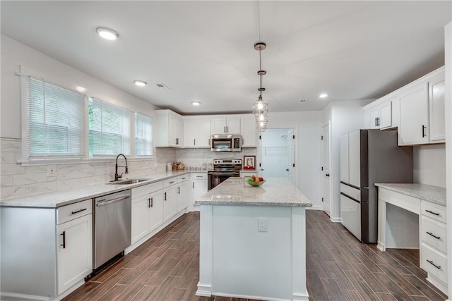 kitchen with sink, white cabinetry, decorative light fixtures, a center island, and appliances with stainless steel finishes