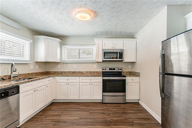 kitchen with sink, white cabinetry, stone countertops, and stainless steel appliances