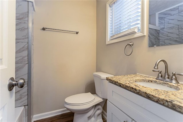 bathroom with wood-type flooring, toilet, vanity, and tiled shower