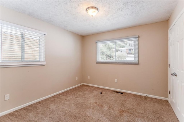 empty room with light carpet and a textured ceiling