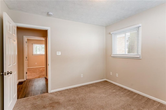 carpeted empty room with a textured ceiling