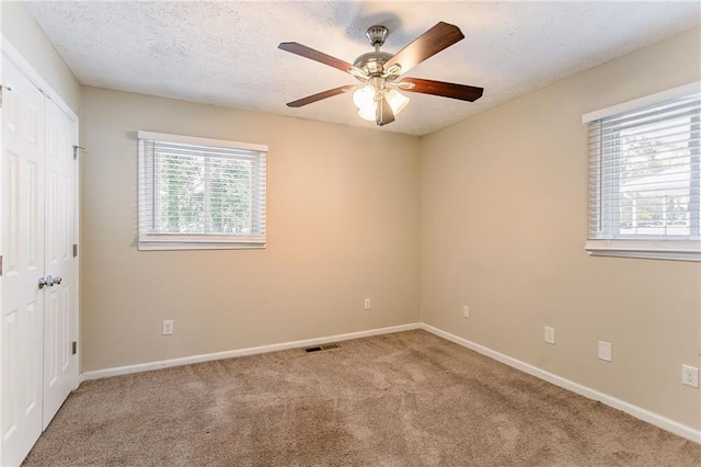 carpeted spare room with ceiling fan and a textured ceiling