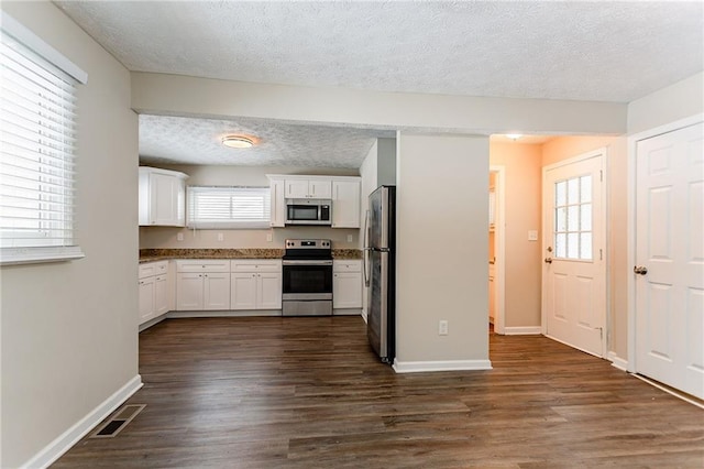 kitchen with white cabinetry, dark hardwood / wood-style flooring, stainless steel appliances, and a textured ceiling