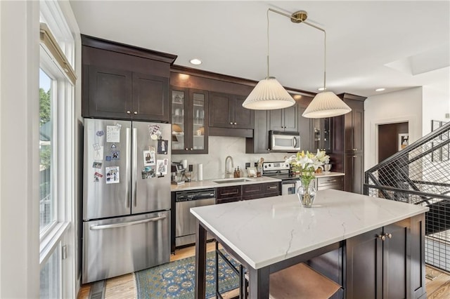 1290 Nervi Mews NW, Atlanta, GA 30318 - kitchen with stainless steel appliances, dark brown cabinets, light wood-style floors, glass insert cabinets, and pendant lighting