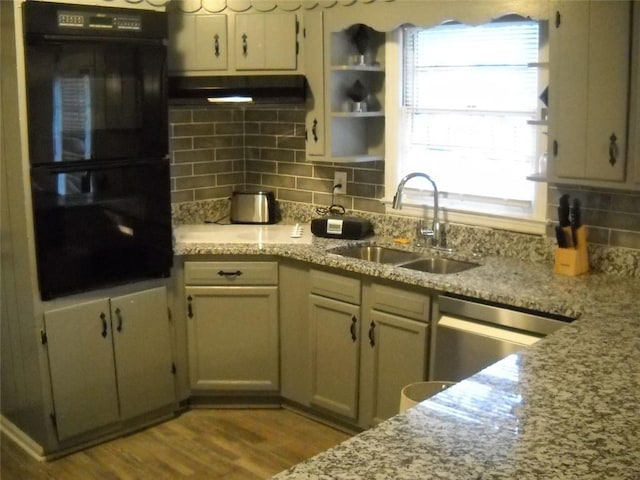 kitchen with light stone counters, sink, backsplash, and black double oven