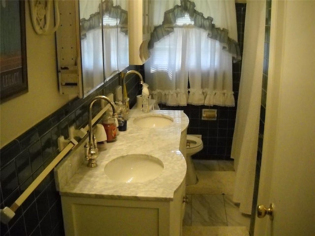 bathroom featuring vanity, toilet, and tile walls