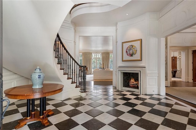 entryway with a decorative wall, stairs, and a fireplace with flush hearth