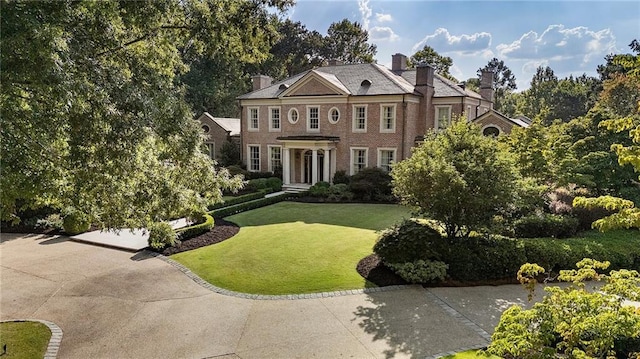 colonial home with a chimney and a front yard