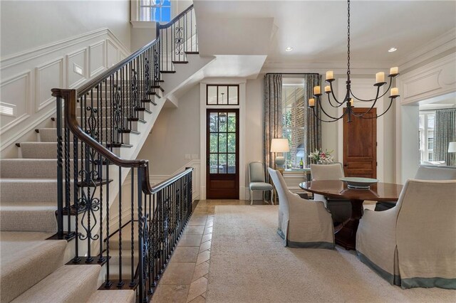 dining area with light colored carpet, plenty of natural light, a notable chandelier, and ornamental molding