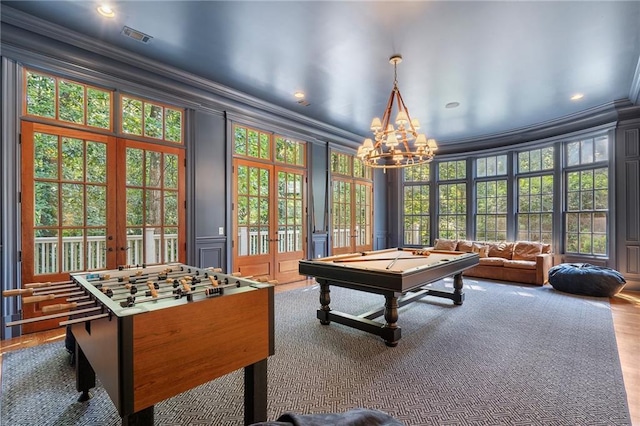 recreation room with visible vents, ornamental molding, french doors, an inviting chandelier, and a decorative wall