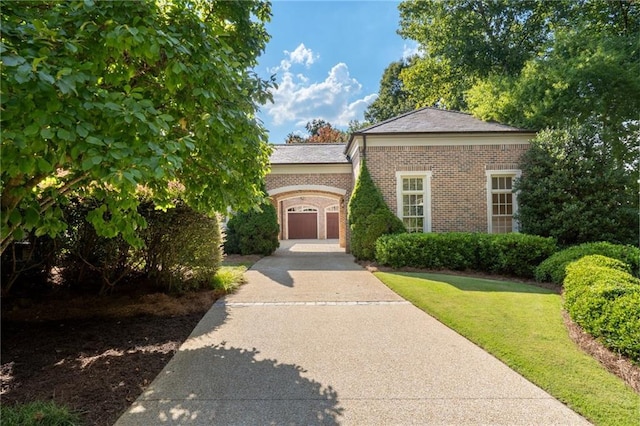 view of front facade featuring brick siding, concrete driveway, and a front lawn