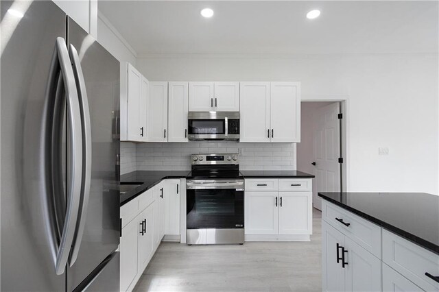 1097 Hubbard St SW, Atlanta, GA 30310 - kitchen with light wood-type flooring, appliances with stainless steel finishes, backsplash, and white cabinetry