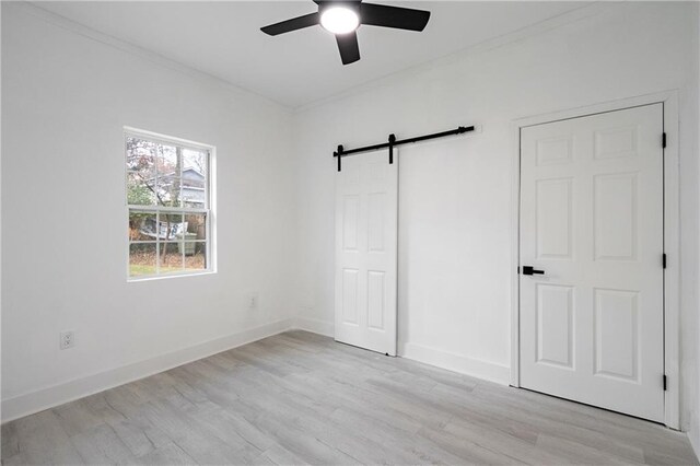 1097 Hubbard St SW, Atlanta, GA 30310 - unfurnished bedroom with ceiling fan, a barn door, light hardwood / wood-style floors, and crown molding