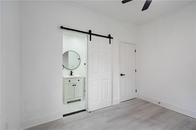 1097 Hubbard St SW, Atlanta, GA 30310 - unfurnished bedroom featuring a barn door, light hardwood / wood-style flooring, ceiling fan, and sink