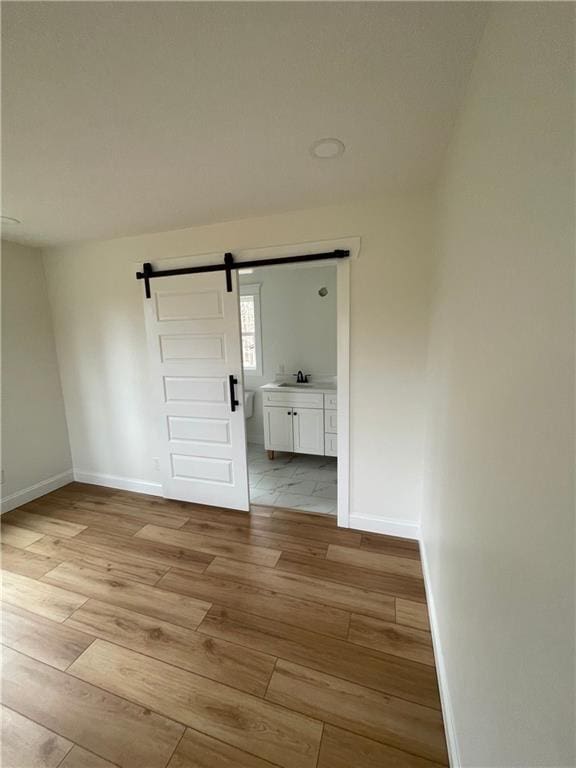 446 Brown Bridge Rd, Chatsworth, GA 30705 - spare room featuring light wood-style flooring, a barn door, baseboards, and a sink