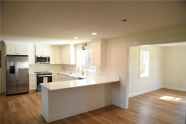 446 Brown Bridge Rd, Chatsworth, GA 30705 - kitchen with stainless steel appliances, light countertops, a peninsula, light wood-type flooring, and recessed lighting