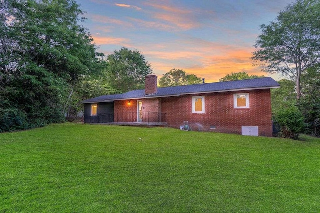 1091 Pine St, Conyers, GA 30012 - back of house at dusk with a lawn, a chimney, crawl space, and brick siding