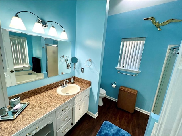 bathroom featuring wood-type flooring, toilet, vanity, and walk in shower