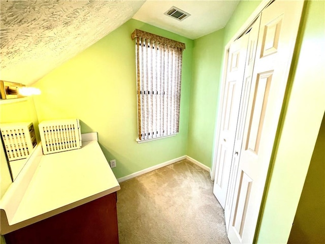 interior space featuring lofted ceiling, carpet flooring, and a textured ceiling