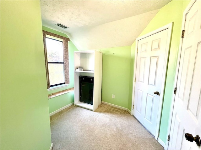 interior space with lofted ceiling, light colored carpet, and a textured ceiling